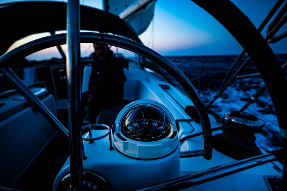Close-up of sailboat steering wheel and compass during twilight navigation.