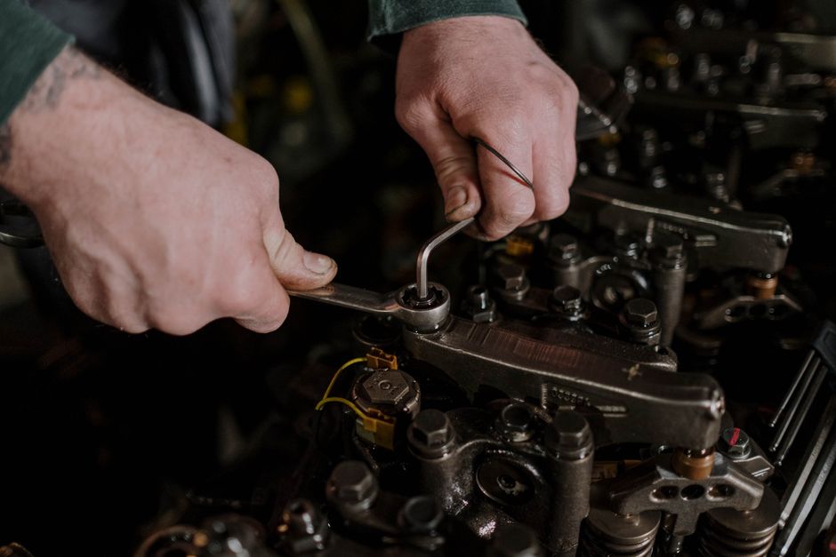Close-up of a mechanic using a wrench and Allen key to fix an engine.