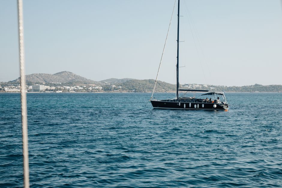 A serene view of a yacht sailing on blue waters with distant coastal hills.